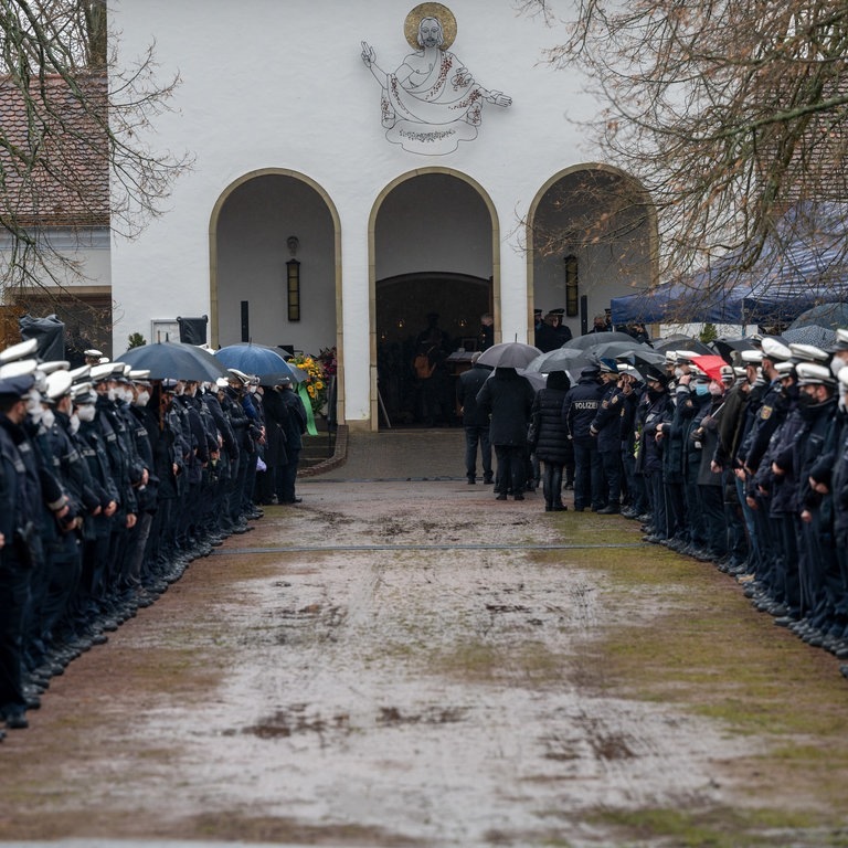 Polizisten und Polizistinnen stehen an der Kirche Spalier beim Gedenkgottesdienst für eine getötete Polizistin. Nach der Bestattung eines ermordeten Polizisten wird nun auch seine getötete Kollegin beigesetzt. Der 29 Jahre alte Polizeikommissar und die 24 Jahre alte Polizeianwärterin waren am 31. Januar während einer Fahrzeugkontrolle bei Kusel erschossen. (Foto: dpa Bildfunk, picture alliance/dpa | Harald Tittel)