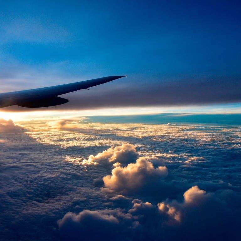 Sicht aus einem Flugzeug auf Wolken im Sonnenuntergang (Foto: IMAGO, IMAGO/YAY Images)