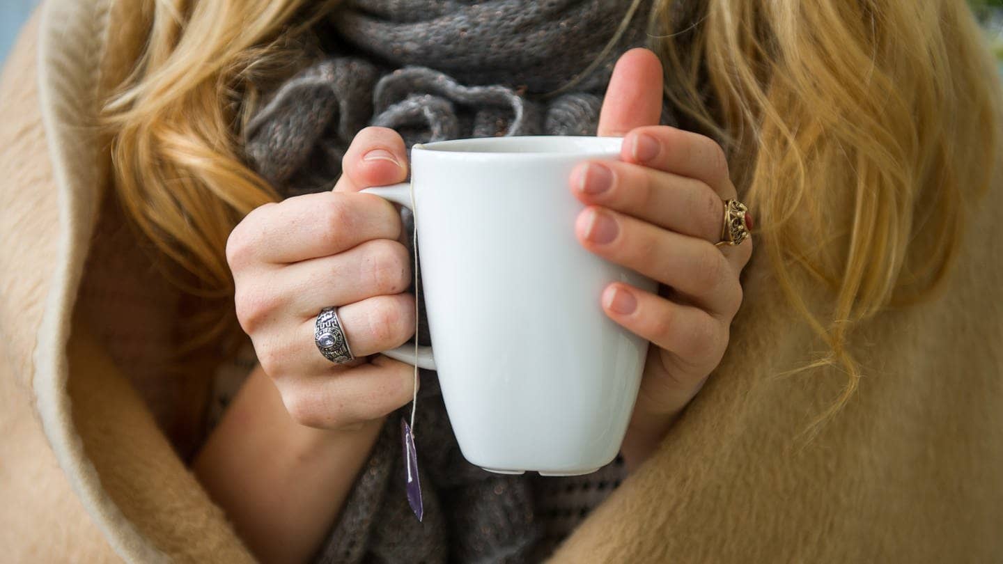 Eine Frau wärmt sich in eine Decke gehüllt, an einer Tasse Tee in den Händen (Foto: dpa Bildfunk, picture alliance / dpa | Ole Spata)