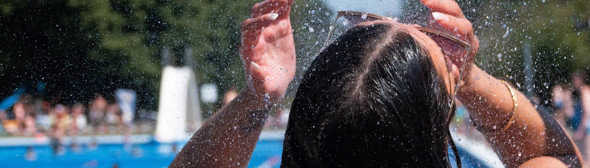 Eine junge Frau kühlt sich bei hochsommerlichen Temperaturen unter der Dusche von einem Schwimmbad ab. (Foto: dpa Bildfunk, picture alliance/dpa | Hilal Özcan)