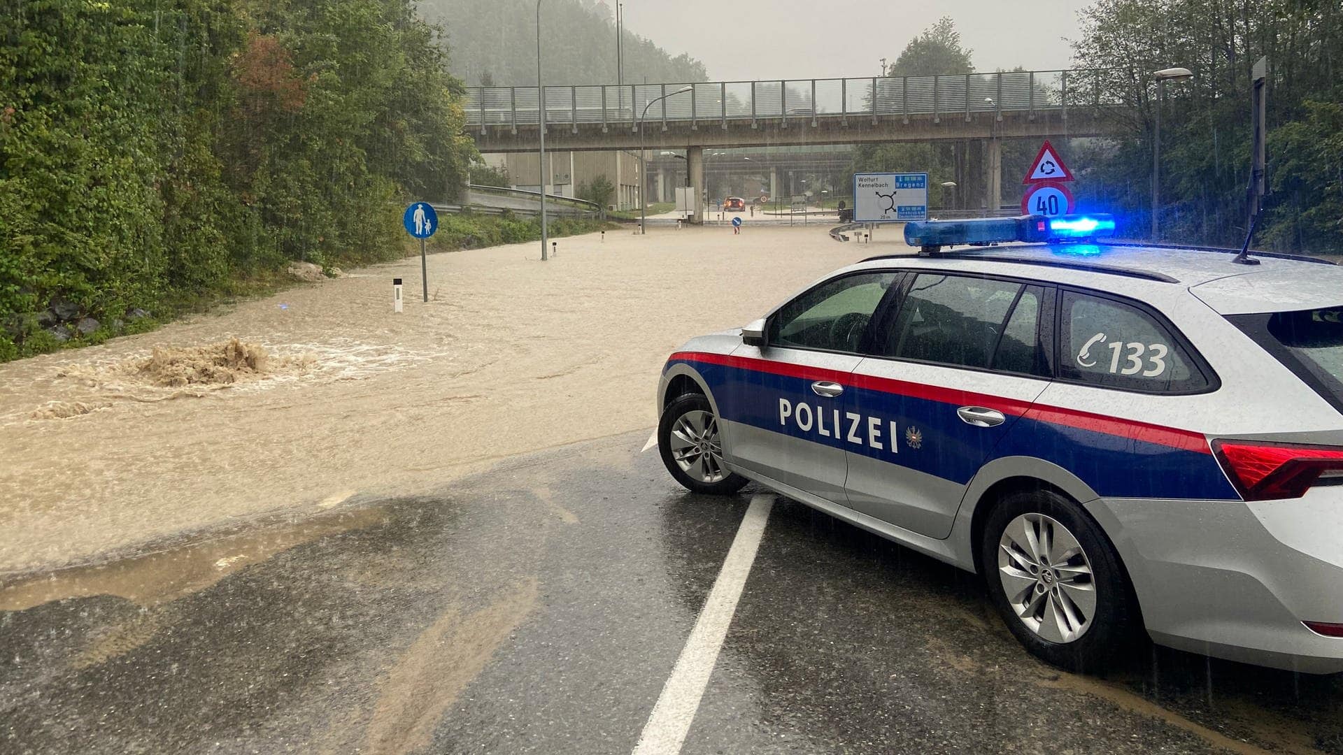 Ein Polizeifahrzeug steht nach Starkregen an einer überschwemmten Straße bei Wolfurt in der Nähe von Bregenz, Vorarlberg, Österreich. (Foto: dpa Bildfunk, picture alliance/dpa | Davor Knappmeyer)