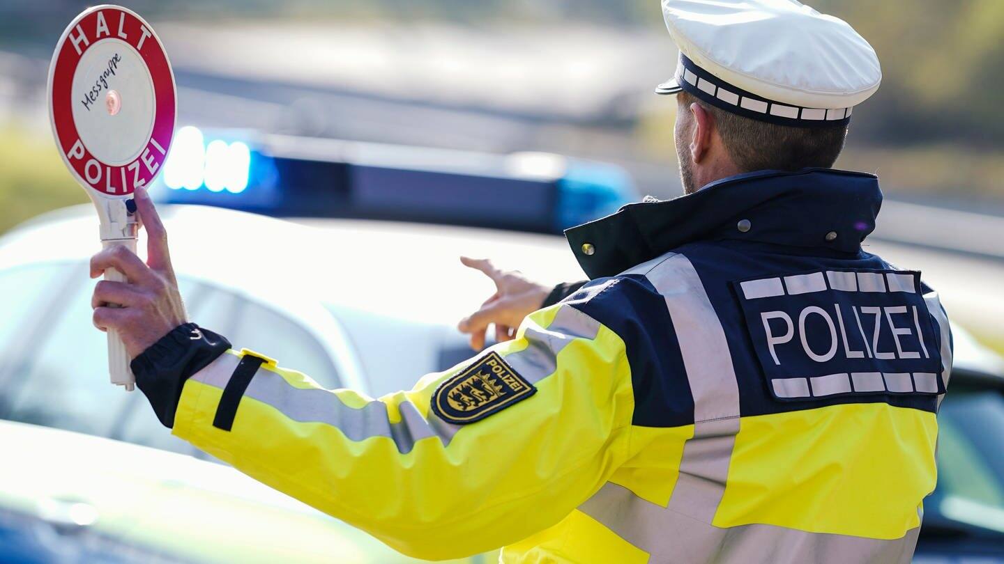 Ein Polizist hebt bei einer Geschwindigkeitskontrolle eine Polizeikelle (Symbolbild) (Foto: dpa Bildfunk, picture alliance/dpa | Uwe Anspach )