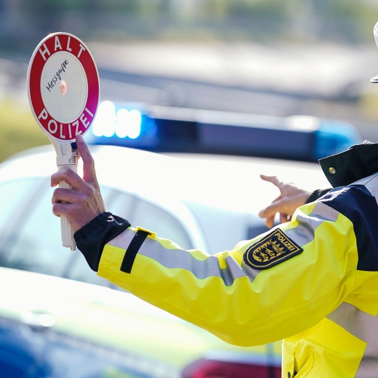 Ein Polizist hebt bei einer Geschwindigkeitskontrolle eine Polizeikelle (Symbolbild) (Foto: dpa Bildfunk, picture alliance/dpa | Uwe Anspach )