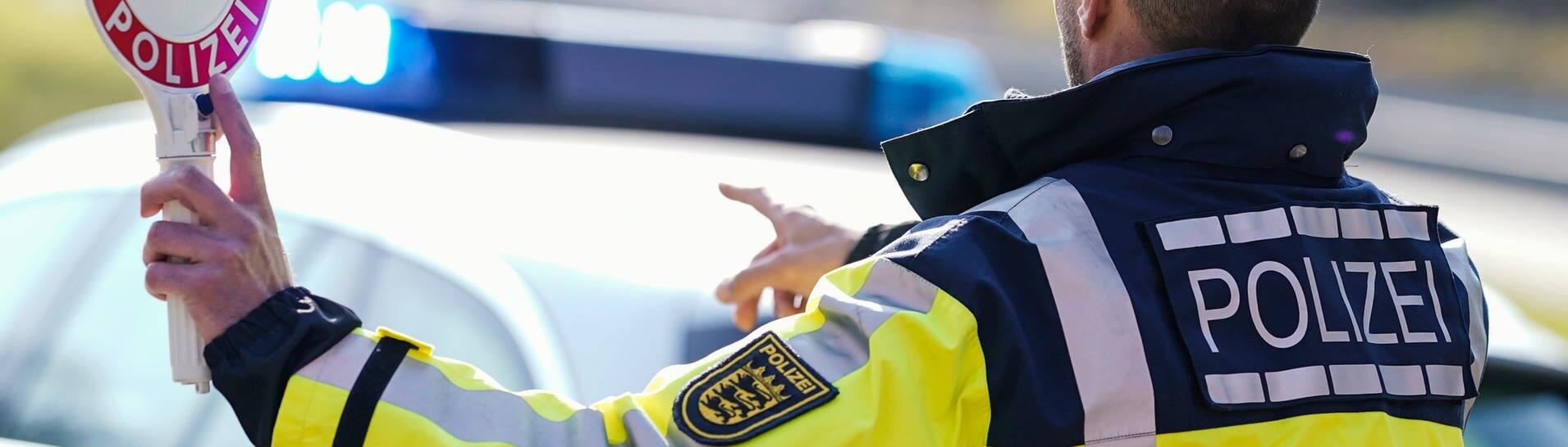 Ein Polizist hebt bei einer Geschwindigkeitskontrolle eine Polizeikelle (Symbolbild) (Foto: dpa Bildfunk, picture alliance/dpa | Uwe Anspach )