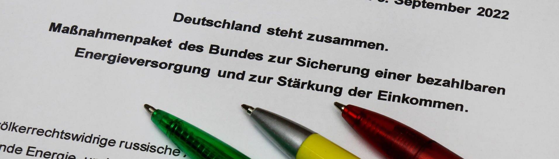 Ein roter, gelber und grüner Kugelschreiber liegen auf dem ausgedruckten Beschluss des Entlastungspakets (Foto: IMAGO, IMAGO/Steinach)