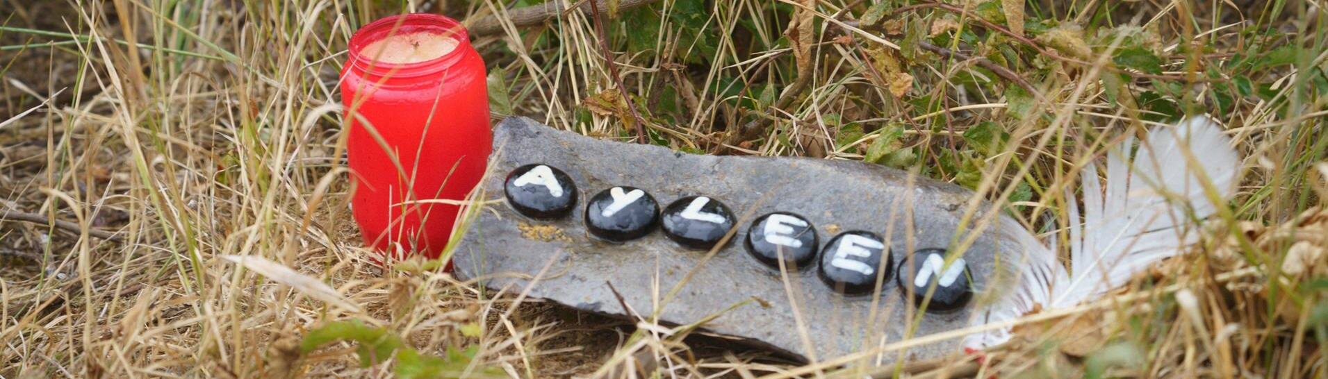 Steine mit Ayleens Namen und eine Kerze stehen auf einer Wiese (Foto: dpa Bildfunk, picture alliance/dpa | Frank Rumpenhorst)