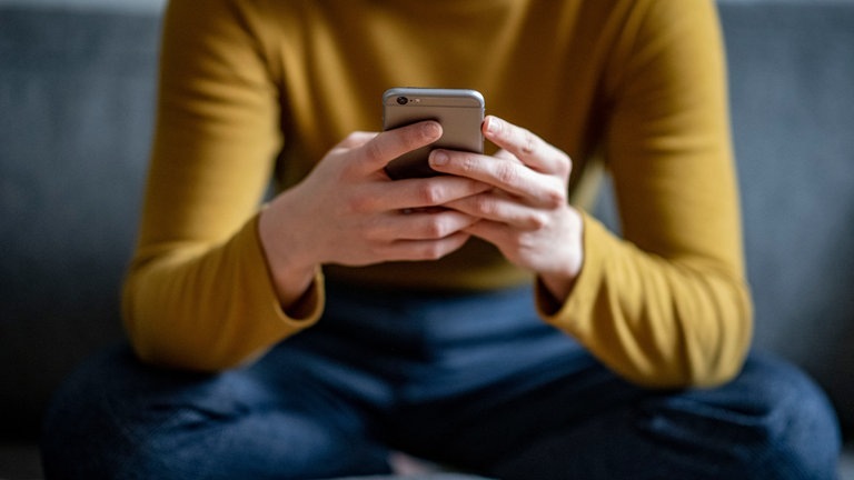 Eine junge Frau hält ein Smartphone in der Hand. (Foto: dpa Bildfunk, picture alliance/dpa | Fabian Sommer)