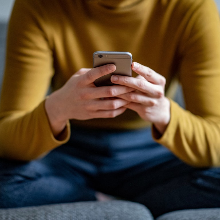 Eine junge Frau hält ein Smartphone in der Hand. (Foto: dpa Bildfunk, picture alliance/dpa | Fabian Sommer)