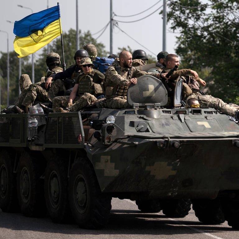 Ukrainische Soldaten fahren auf einem gepanzerten Fahrzeug auf einer Straße. (Foto: dpa Bildfunk, picture alliance/dpa/AP | Leo Correa)