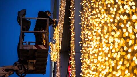 Ein Mann hängt am Königsbau in Stuttgart (Baden-Württemberg) von einer Hebebühne Weihnachtsbeleuchtung auf. (Foto: dpa Bildfunk, picture alliance / dpa | Wolfram Kastl)
