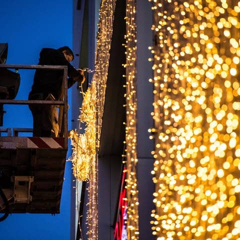 Ein Mann hängt am Königsbau in Stuttgart (Baden-Württemberg) von einer Hebebühne Weihnachtsbeleuchtung auf. (Foto: dpa Bildfunk, picture alliance / dpa | Wolfram Kastl)