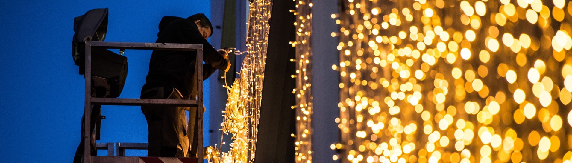 Ein Mann hängt am Königsbau in Stuttgart (Baden-Württemberg) von einer Hebebühne Weihnachtsbeleuchtung auf. (Foto: dpa Bildfunk, picture alliance / dpa | Wolfram Kastl)