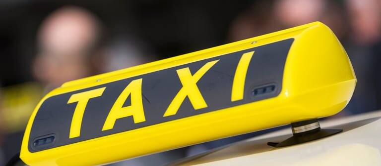 Großes Taxischild auf einem Taxi. (Foto: dpa Bildfunk, picture alliance/dpa | Christophe Gateau)