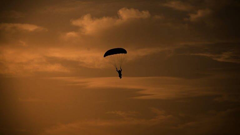 Ein Mensch springt mit einem Fallschirm (Symbolbild). (Foto: IMAGO, IMAGO / SNA)