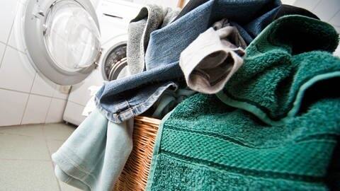 Ein Berg Wäsche vor einer Waschmaschine (Foto: picture-alliance / Reportdienste, picture alliance / dpa-tmn | Andrea Warnecke)
