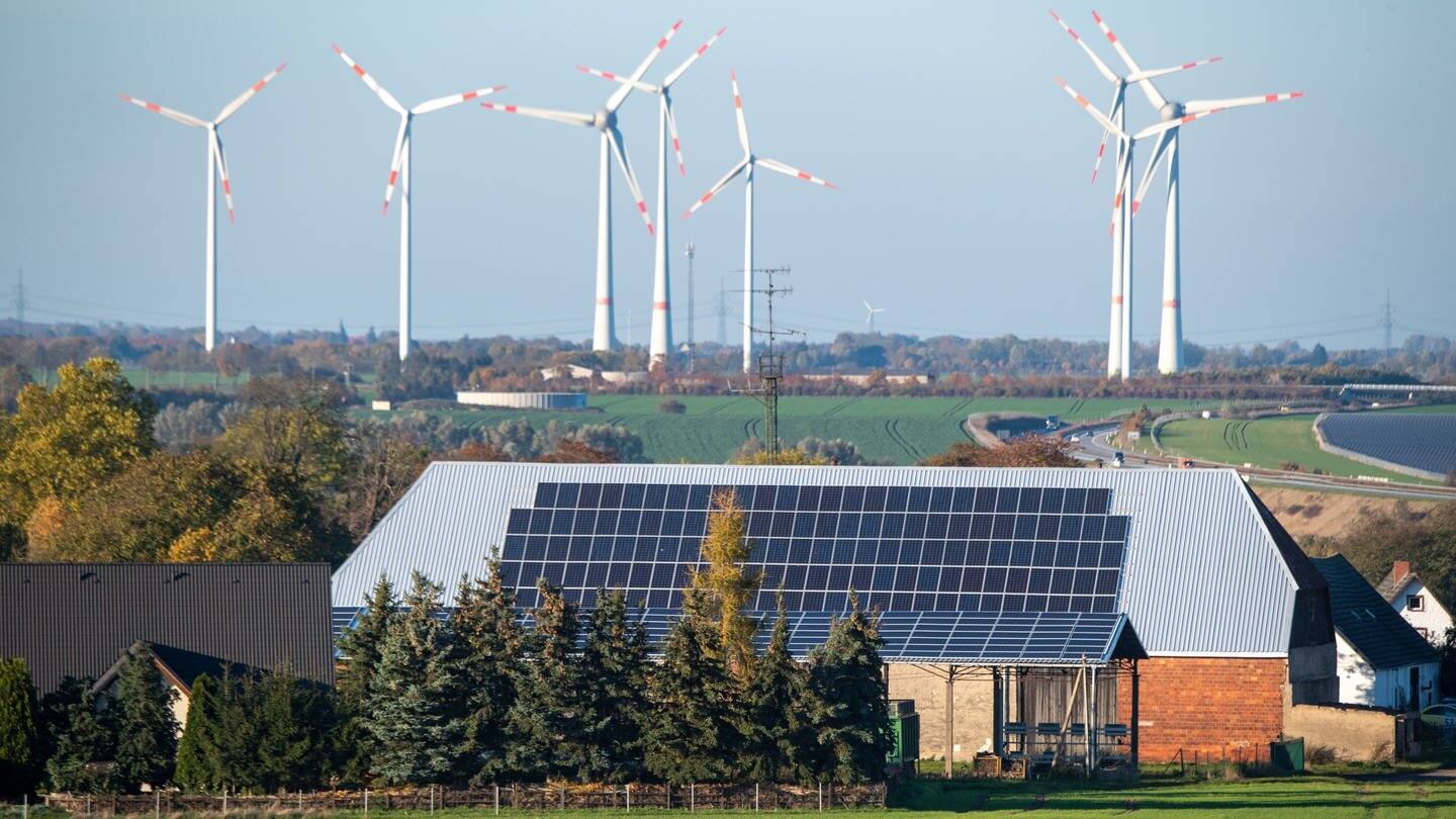 Ein Haus mit Solarpanelen auf dem Dach ist vor Windrädern zu sehen (Foto: dpa Bildfunk, picture alliance/dpa | Stefan Sauer)