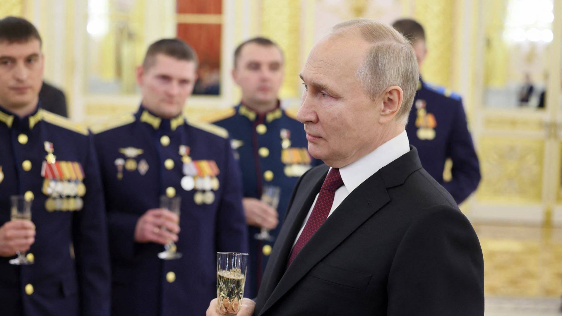 Wladimir Putin steht mit einem Sektglas in der Hand vor Soldaten in einem prunkvollen Zimmer im Kreml.  (Foto: Reuters)