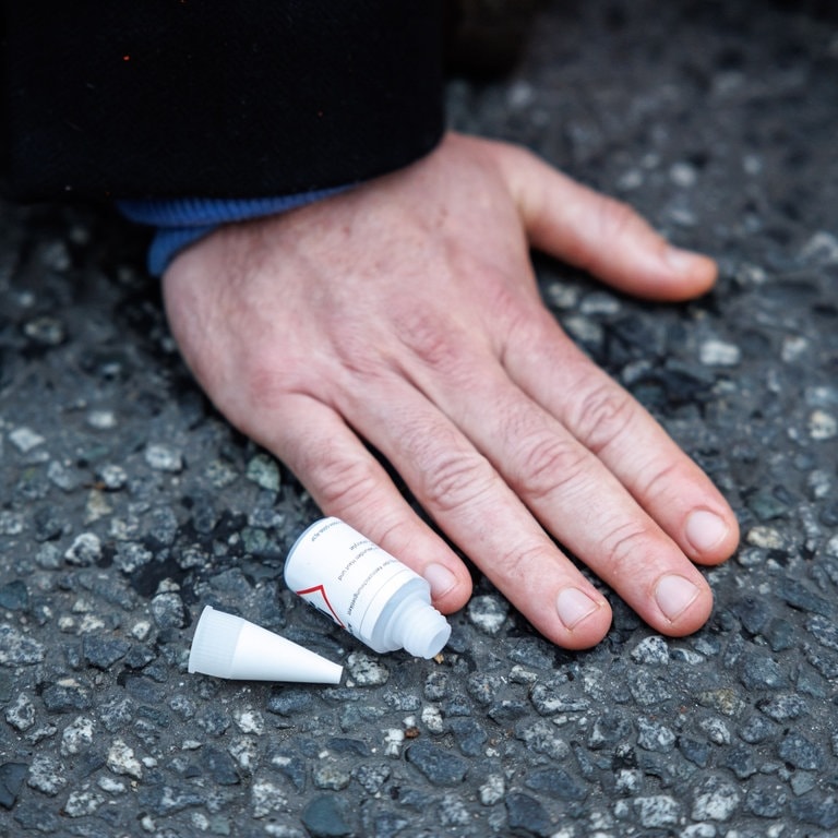 Ein Aktivist der Klimaschutz-Initiative „Letzte Generation“ hat sich am Stachus mit seiner Hand auf die Straße geklebt. Nahaufnahme der Hand. (Foto: dpa Bildfunk, picture alliance/dpa | Matthias Balk)