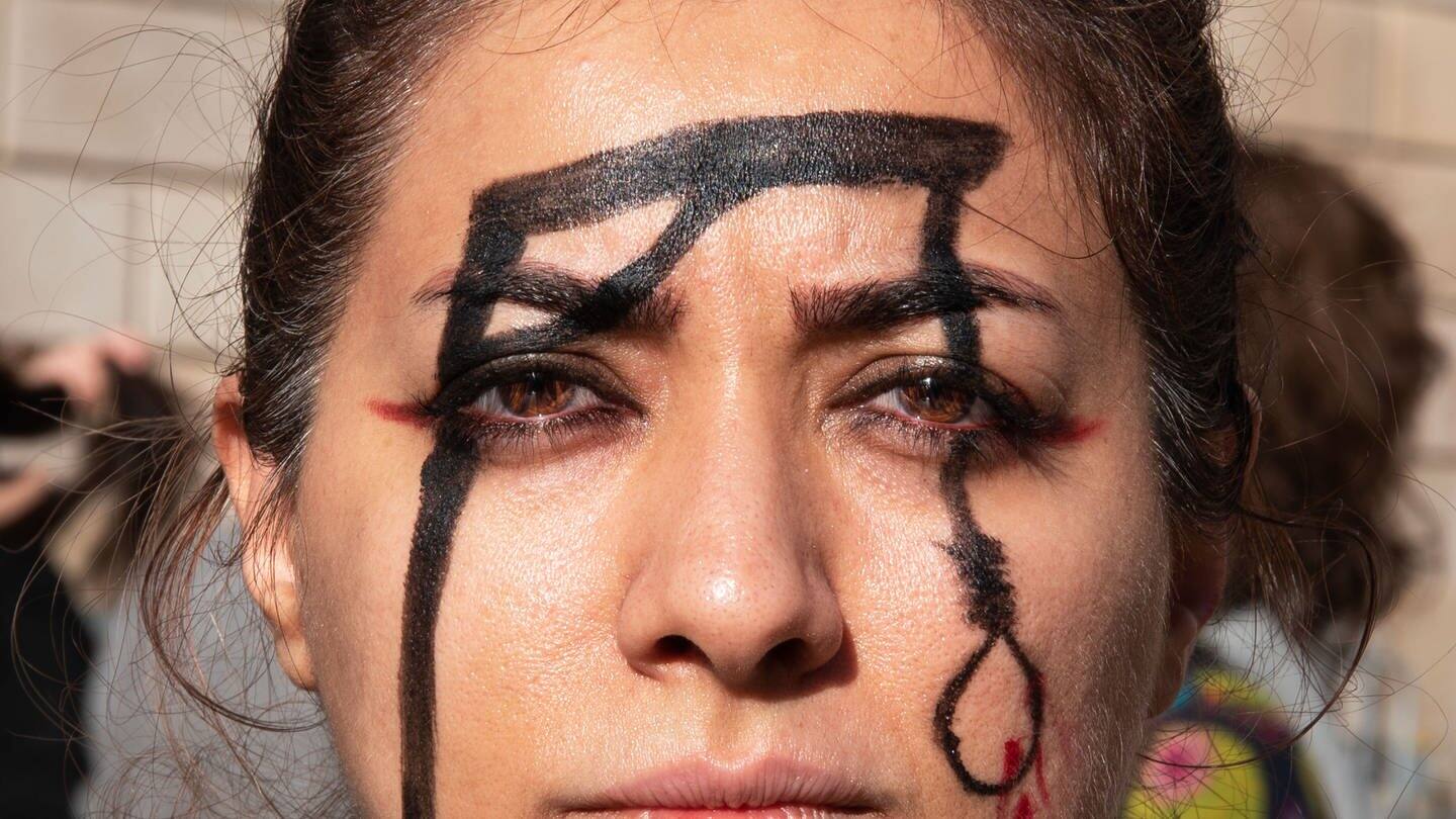 Eine Frau hat einen Galgen auf ihr Gesicht gemalt, um während der Demonstration an die Ermordung von Mohsen Shekari zu erinnern. (Foto: dpa Bildfunk, picture alliance/dpa/SOPA Images via ZUMA Press Wire | Ximena Borrazas)
