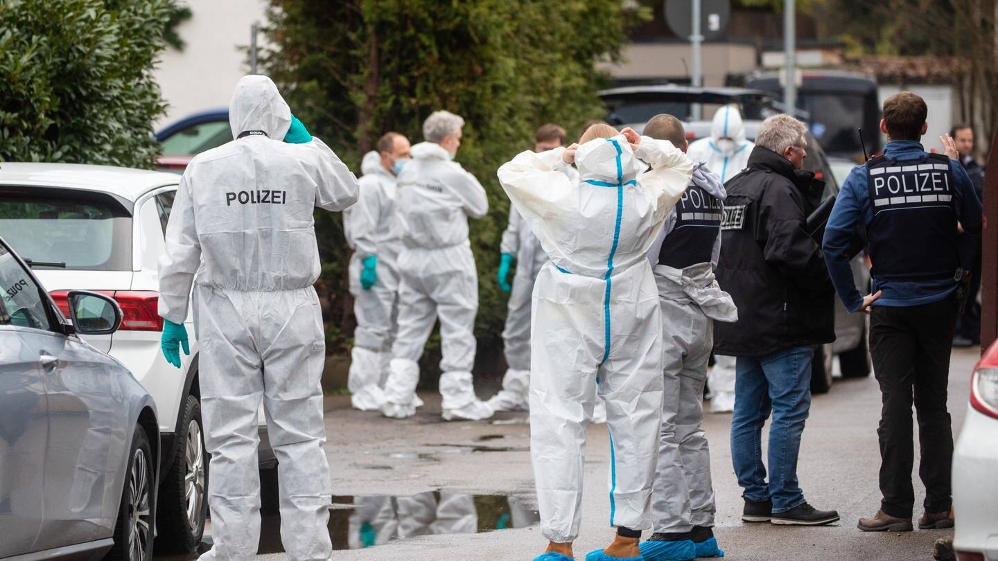 Einsatzkräfte der Spurensicherung in weißen Anzügen arbeiten am Tatort.