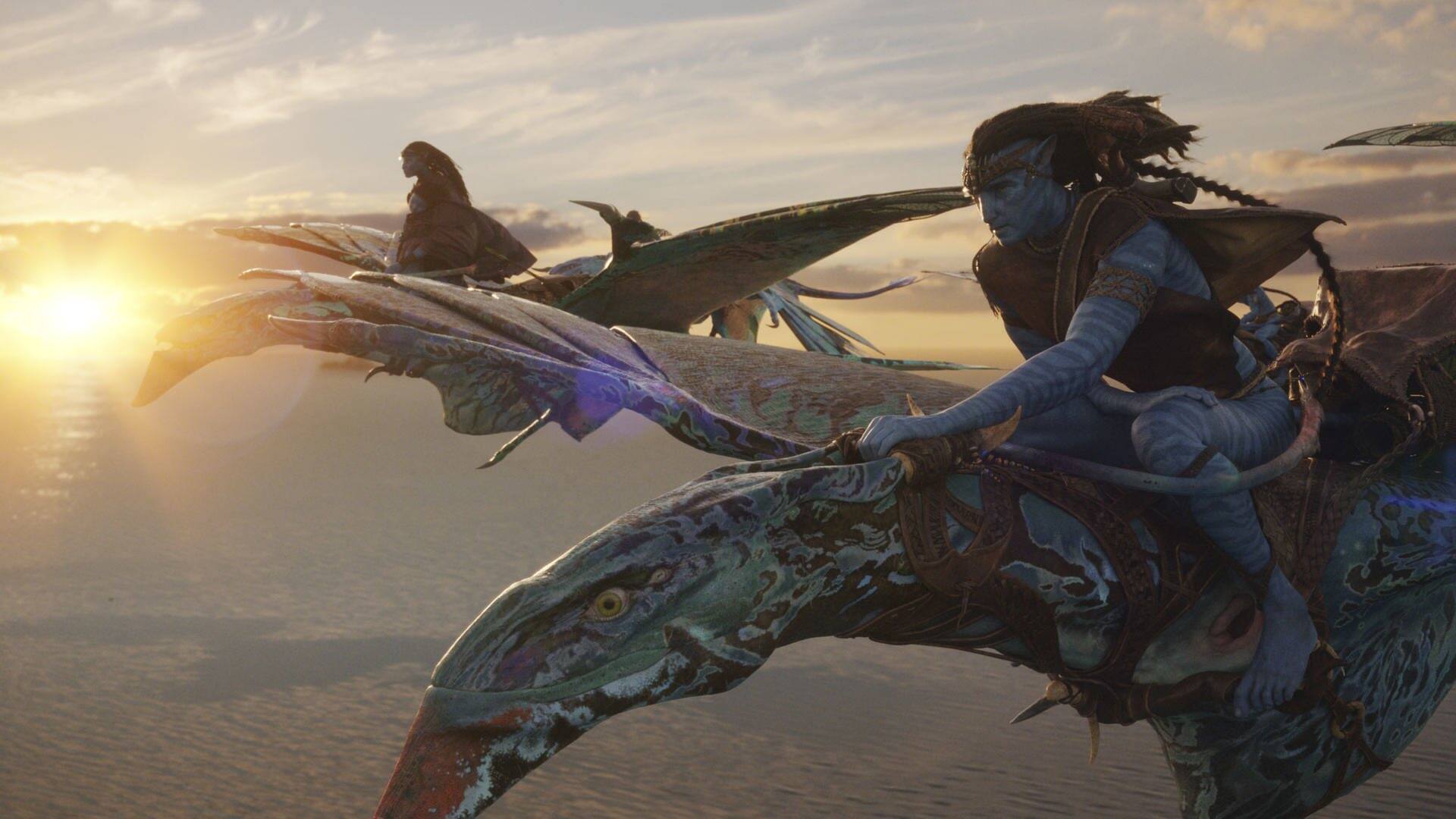 Szenenbild aus dem Film Avatar: Zwei Figuren reiten auf fliegenden Drachen im Sonnenuntergang (Foto: Disney)