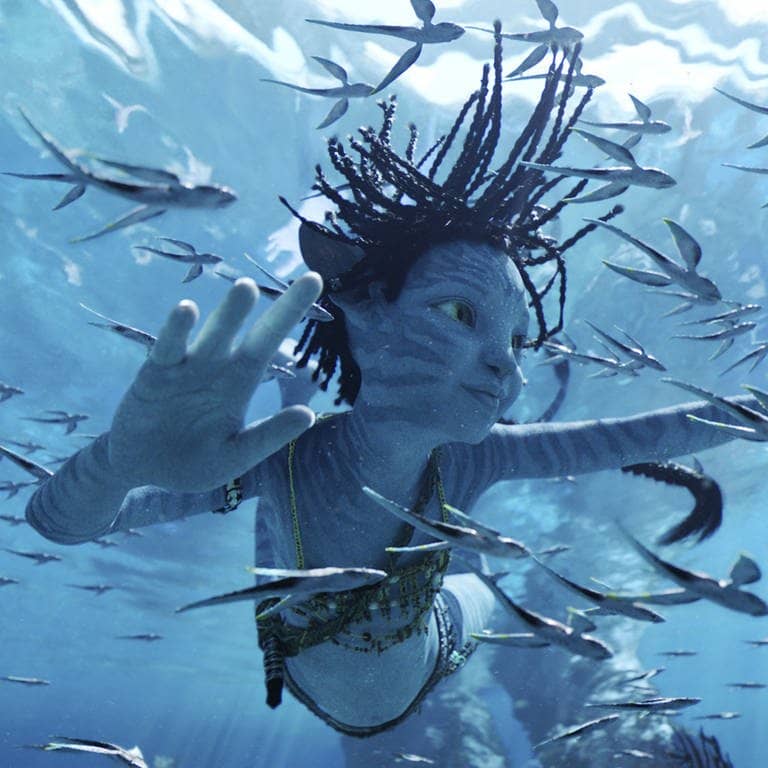 Szenenbild aus dem Film Avatar 2: Unterwasseraufnahme. Figur schwimmt mit einem Schwarm Fische. (Foto: Disney)
