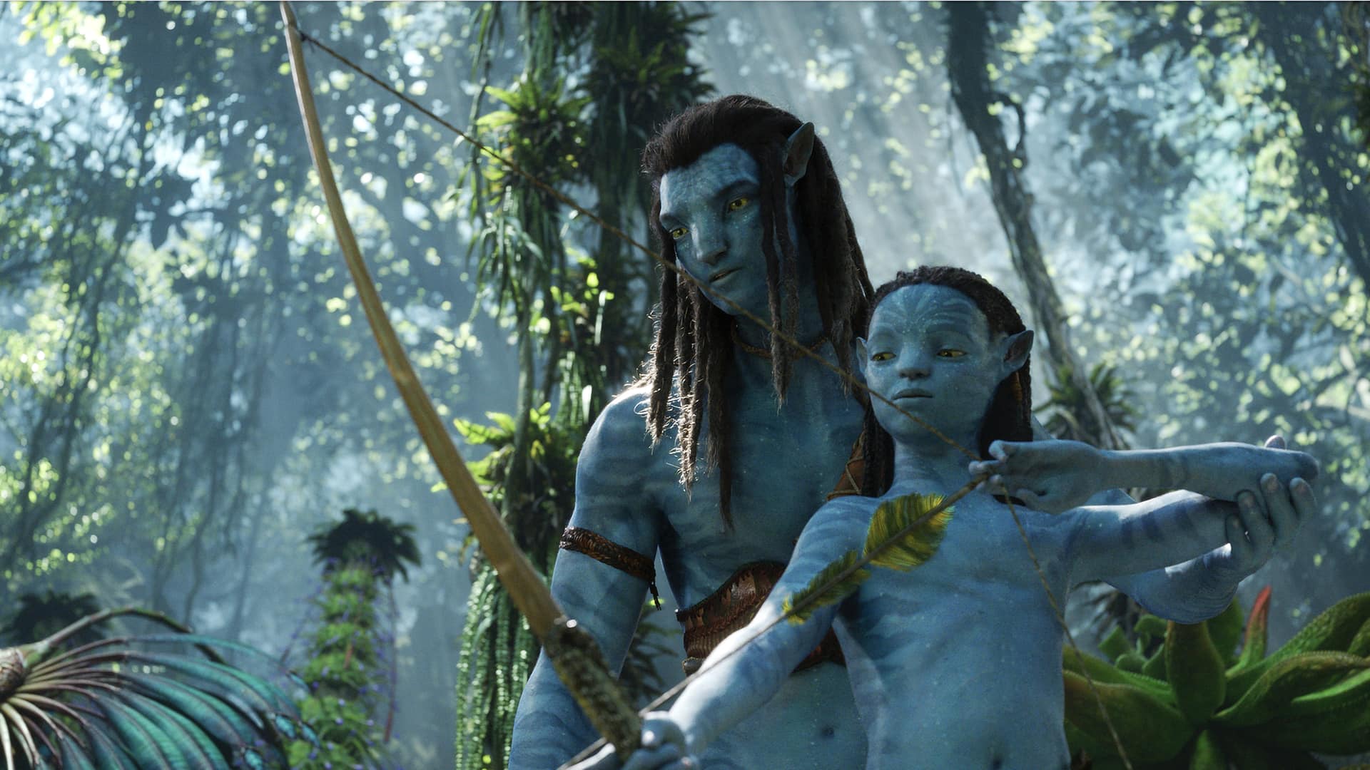 Szenenbild aus dem Film Avatar 2: Ein Mann und ein Kind mit Pfeil und Bogen im Wald. (Foto: Disney)