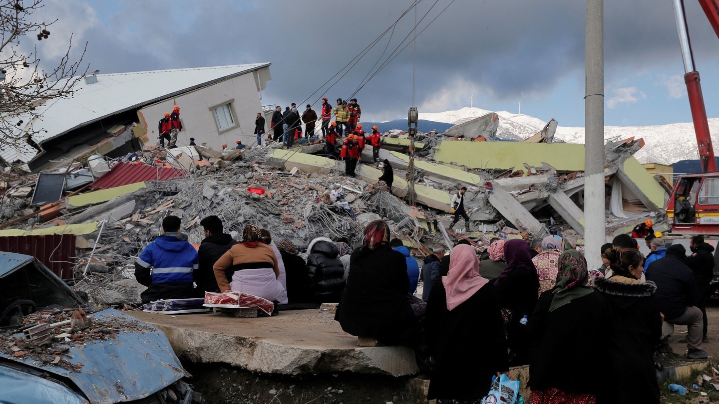 Menschen sitzen vor einem eingestürzten Gebäude in Gaziantep. (Foto: Reuters)