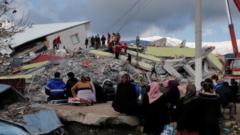 Menschen sitzen vor einem eingestürzten Gebäude in Gaziantep. (Foto: Reuters)
