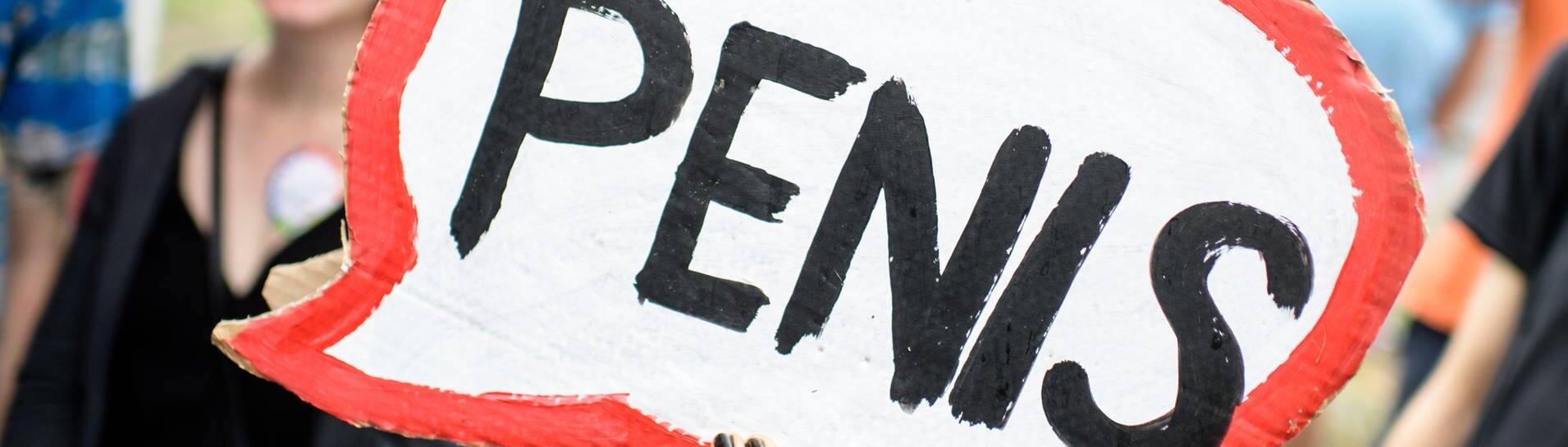 Eine Frau hebt bei einer CSD-Parade ein Schild mit der Aufschrift „Penis“ (Foto: dpa Bildfunk, picture alliance/dpa | Matthias Balk)