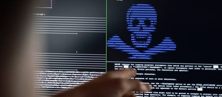 Auf einem PC-Monitor ist ein blauer Totenkopf aus Buchstaben vor schwarzem Grund wie bei einer Cyberattacke (Foto: dpa Bildfunk, picture alliance/dpa | Frank Rumpenhorst)