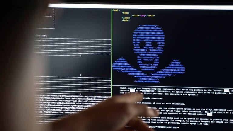 Auf einem PC-Monitor ist ein blauer Totenkopf aus Buchstaben vor schwarzem Grund wie bei einer Cyberattacke (Foto: dpa Bildfunk, picture alliance/dpa | Frank Rumpenhorst)