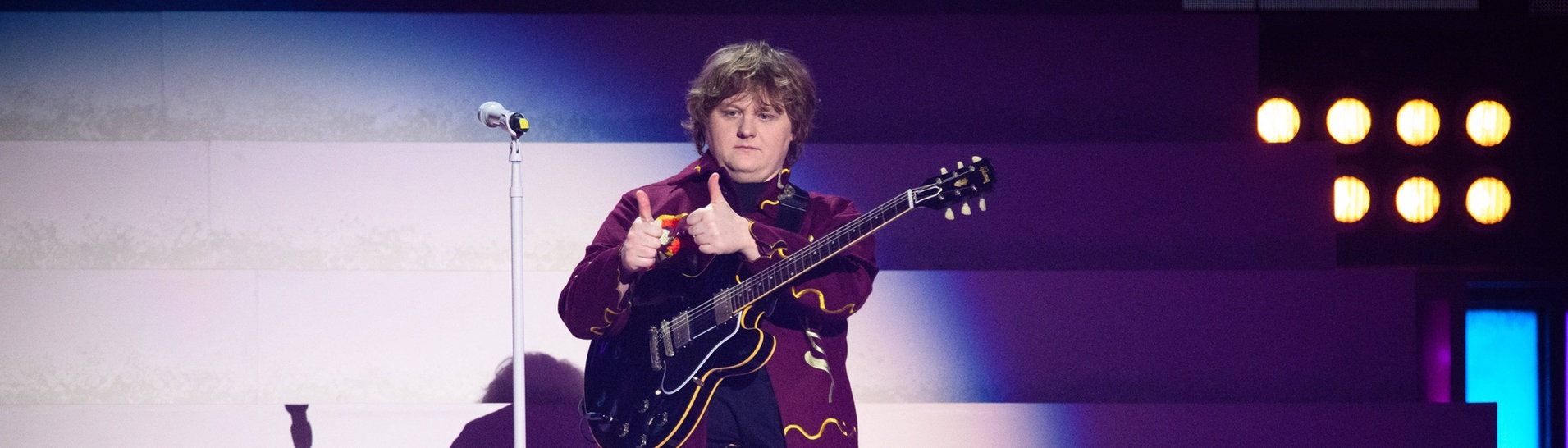 Der Sänger Lewis Capaldi steht mit einer Gitarre auf der Bühne bei den Brit Awards 2023.  (Foto: IMAGO, IMAGO / PA Images)