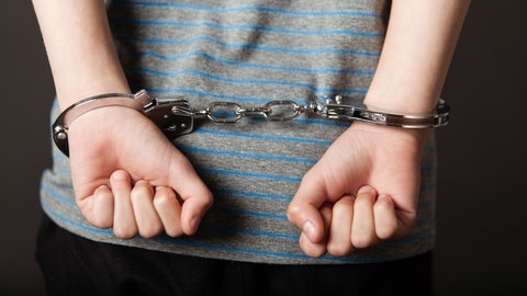Ein Kind von hinten mit Handschellen an den Armen hinter dem Rücken (Foto: Adobe Stock, Jan H. Andersen)