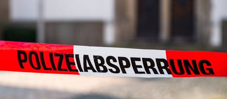 „Polizeiabsperrung“ steht auf einem rot-weißen Flatterband der Polizei.  (Foto: dpa Bildfunk, picture alliance/dpa | Daniel Vogl)