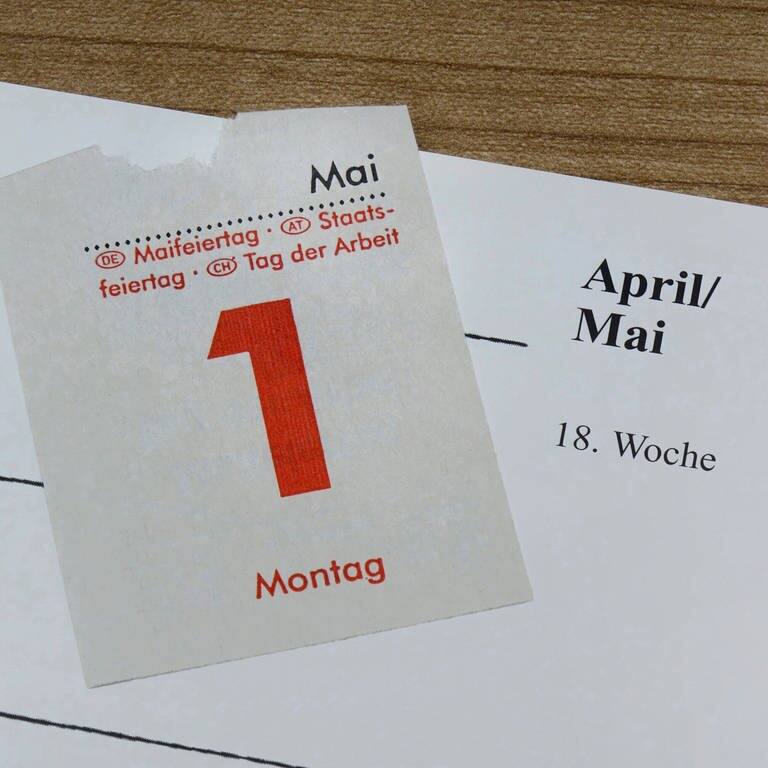 Ein Kalenderblatt des 1. Mais liegt auf einem Tischkalender, auf dessen Blatt "AprilMai" steht (Foto: IMAGO, IMAGO/Steinach)