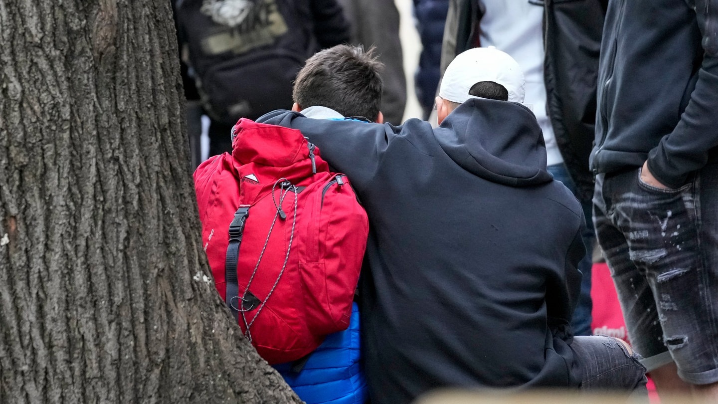 Foto: dpa Bildfunk, picture alliance/dpa/AP | Darko Vojinovic Nach Schüssen in Schule in Belgrad: Jugendliche sitzen an einem Baum und umarmen sich (Foto: dpa Bildfunk, picture alliance/dpa/AP | Darko Vojinovic)