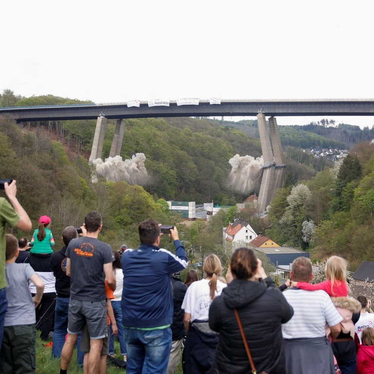Menschen schauen aus der Ferne zu, wie die marode Rahmedetalbrücke bei Lüdenscheid gesprengt wird (Foto: Reuters, REUTERS/Leon Kuegeler)