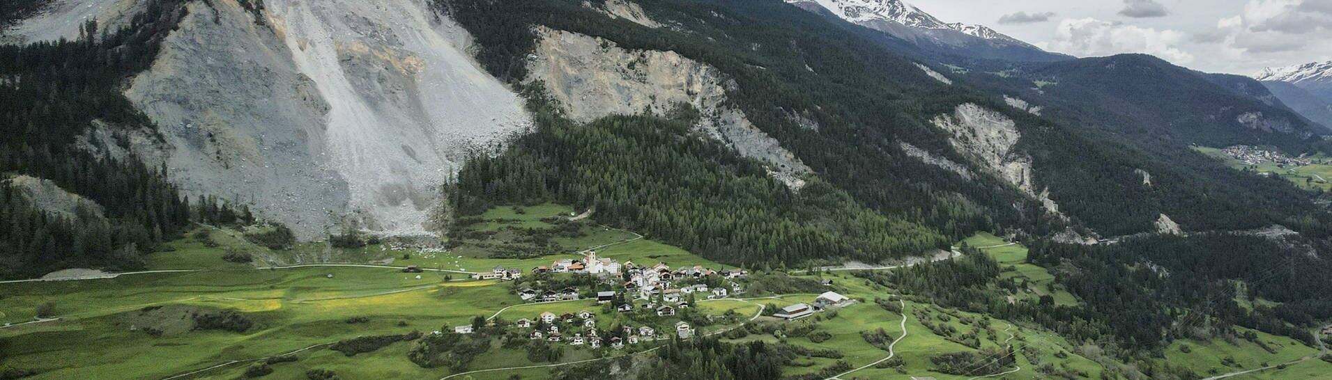 Herabgestürzte Steine und Felsteile (hinten,l) liegen vor dem Dorf Brienz in der Schweiz. (Foto: dpa Bildfunk, picture alliance/dpa/KEYSTONE | Gian Ehrenzeller)