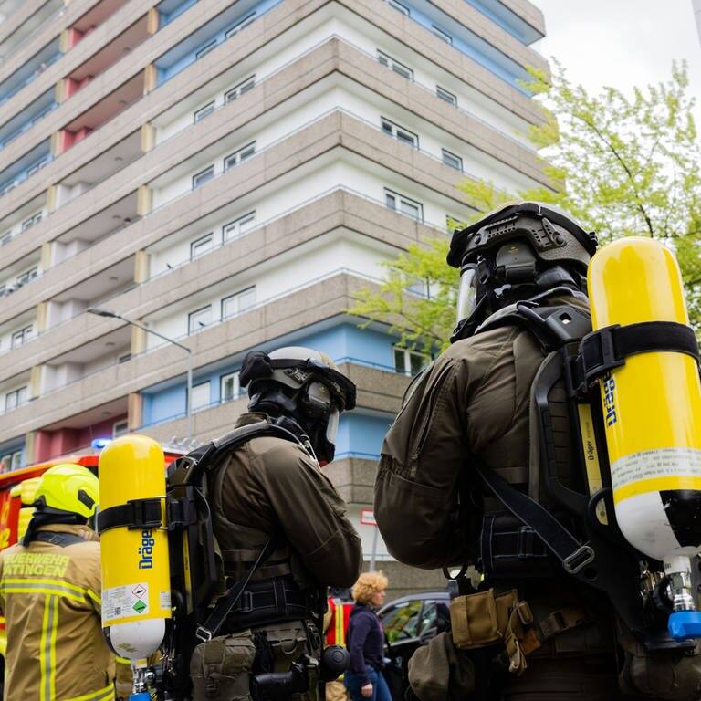 Polizeibeamte mit Gasmasken und Feuerwehrleute stehen vor einem Hochhaus. (Foto: dpa Bildfunk, picture alliance/dpa | Rolf Vennenbernd)