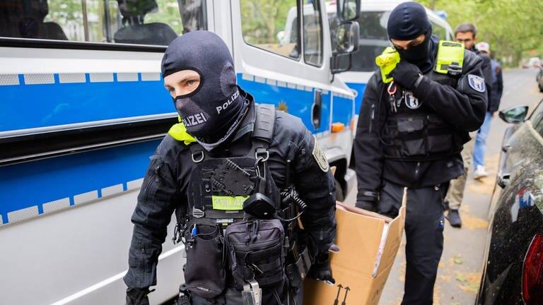 Polizisten tragen während einer Razzia gegen Klimaaktivisten der „Letzten Generation“ einen Karton zu einem Fahrzeug (Foto: dpa Bildfunk, picture alliance/dpa | Christoph Soeder)