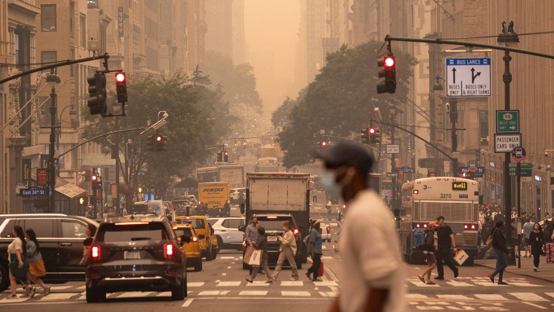 Ein Mann trägt eine FFP2-Maske, während er eine Kreuzung von Manhattan überquert. Waldbrände in Kanada hüllen den Nordosten der USA in Dunst und verfärben den Himmel. (Foto: dpa Bildfunk, picture alliance/dpa/AP | Yuki Iwamura)