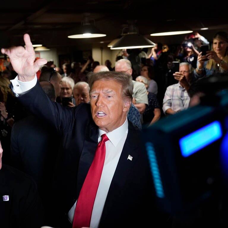 Donald Trump (M), ehemaliger Präsident der USA, begrüßt seine Anhänger vor seiner Rede in Des Moines. (Foto: dpa Bildfunk, picture alliance/dpa/AP | Charlie Neibergall)