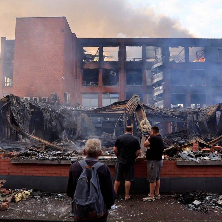 Passanten betrachten ein niedergebranntes Gebäude in der der Stadt Roubaix. (Foto: Reuters)