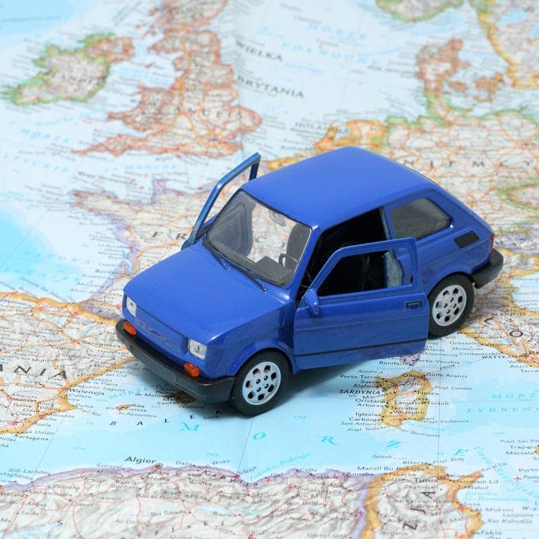 Ein Auto steht auf einer Straßenkarte von Europa (Foto: IMAGO, IMAGO / YAY Images)