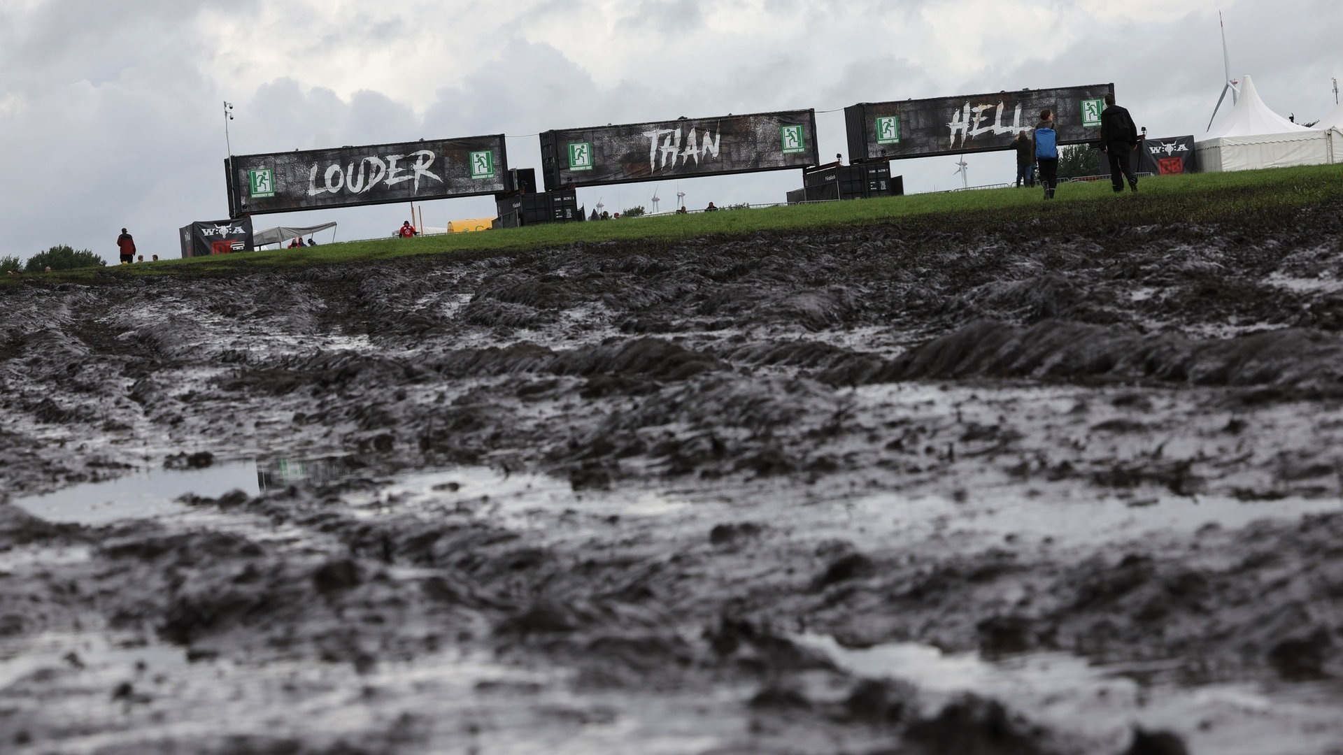 Foto: dpa Bildfunk, picture alliance/dpa | Christian Charisius Banner mit der Aufschrift „Louder than hell“ vor einer matschigen Fläche (Foto: dpa Bildfunk, picture alliance/dpa | Christian Charisius)