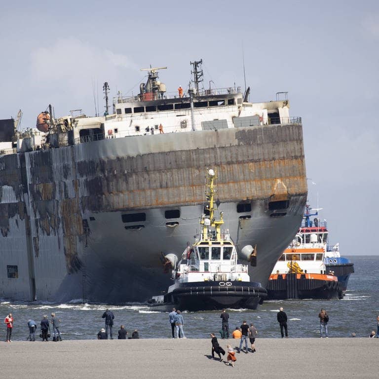 Der stark beschädigte Frachter „Fremantle Highway“ wird von zwei Schleppern in einen Hafen gezogen (Foto: IMAGO, IMAGO/ANP)