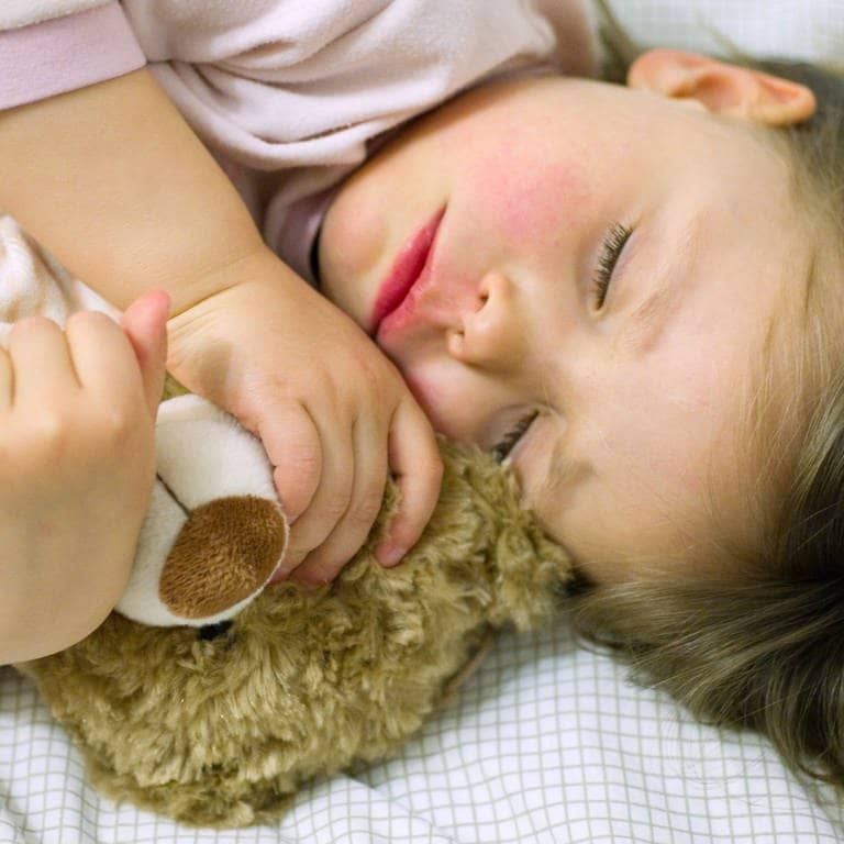 Notaufnahme soll Gebühren kosten? Ein kleines Mädchen mit roten Wangen schläft mit ihrem Teddy im Arm. (Foto: dpa Bildfunk, picture alliance / dpa | Patrick Pleul)