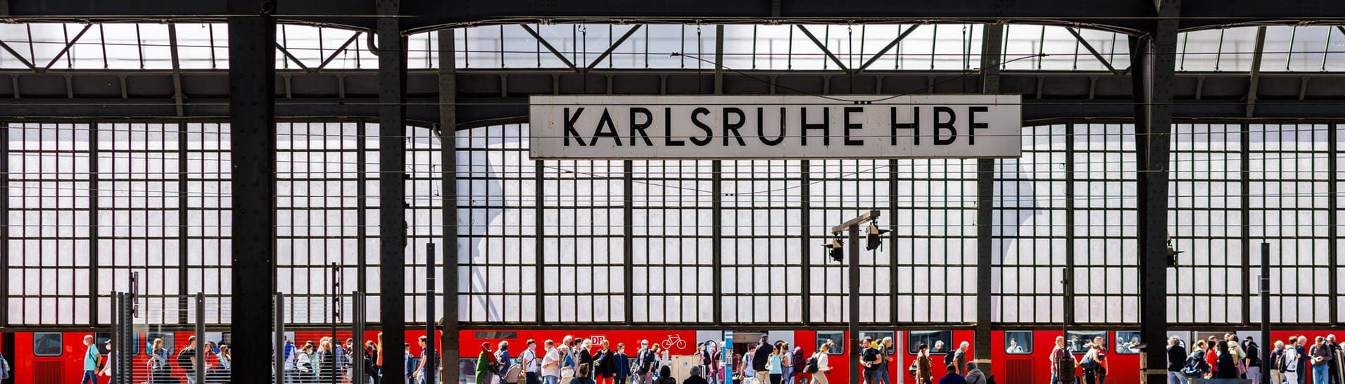 Stromschlag im Zug: Menschen gehen neben einem RE Regionalexpress der DB Deutschen Bahn im Karlsruher Hauptbahnhof über einen Bahnsteig während im Vordergrund Menschen auf einer Bank sitzen. (Foto: dpa Bildfunk, picture alliance/dpa | Philipp von Ditfurth)