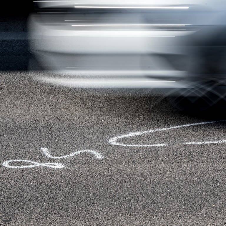 Symbolbild illegales Autorennen: Auto fährt über die Markierungen der Spurensicherung (Foto: dpa Bildfunk, picture alliance / Federico Gambarini/dpa | Federico Gambarini)